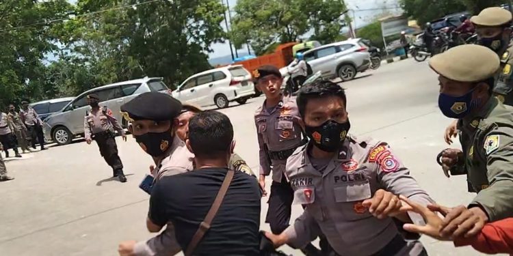 Ketgam: Seorang jurnalis, Ronal (baju hitam) mengamankan polisi yang terlibat cekcok saat demo di Rujab Gubernur Sultra. Foto: Herlis