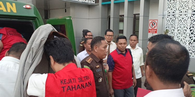 Tersangka Kadis PU Butur (tutupi kepala) saat masuk ke mobil tahanan