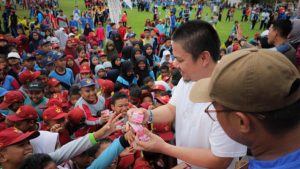 Bupati Kolaka Timur, Abd Azis, membagikan susu kepada para pelajar saat pembukaan O2SN, FLS3N, serta GSI di lapangan sepak bola Desa Gunung Jaya, Kecamatan Dangia, Jumat (11/7/2025). (Foto: Istimewa)