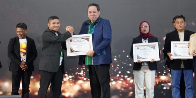 Anggota Bawaslu RI, Herwyn Malonda berikan Penghargaan Nasional kepada Bahari, S.Si., SH., MP., MH (Anggota Bawaslu Provinsi Sulawesi Tenggara) pada Kategori Podcast Kehumasan di Anugerah Bawaslu Tahun 2025, Sabtu (20/12/2025). (Foto: Dok Bawaslu Sultra).