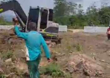 Kakek Hasan berdiri mengadang ekskavator di lokasi kebun yang diduga akan digusur di Desa Puosu Jaya, Kecamatan Konda, Konawe Selatan. (Foto: Istimewa)