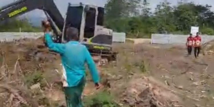Kakek Hasan berdiri mengadang ekskavator di lokasi kebun yang diduga akan digusur di Desa Puosu Jaya, Kecamatan Konda, Konawe Selatan. (Foto: Istimewa)